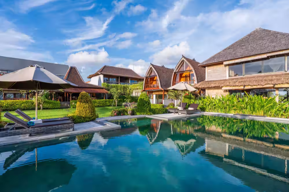 The pool, with the venue’s thatched-roof villas reflected in it
