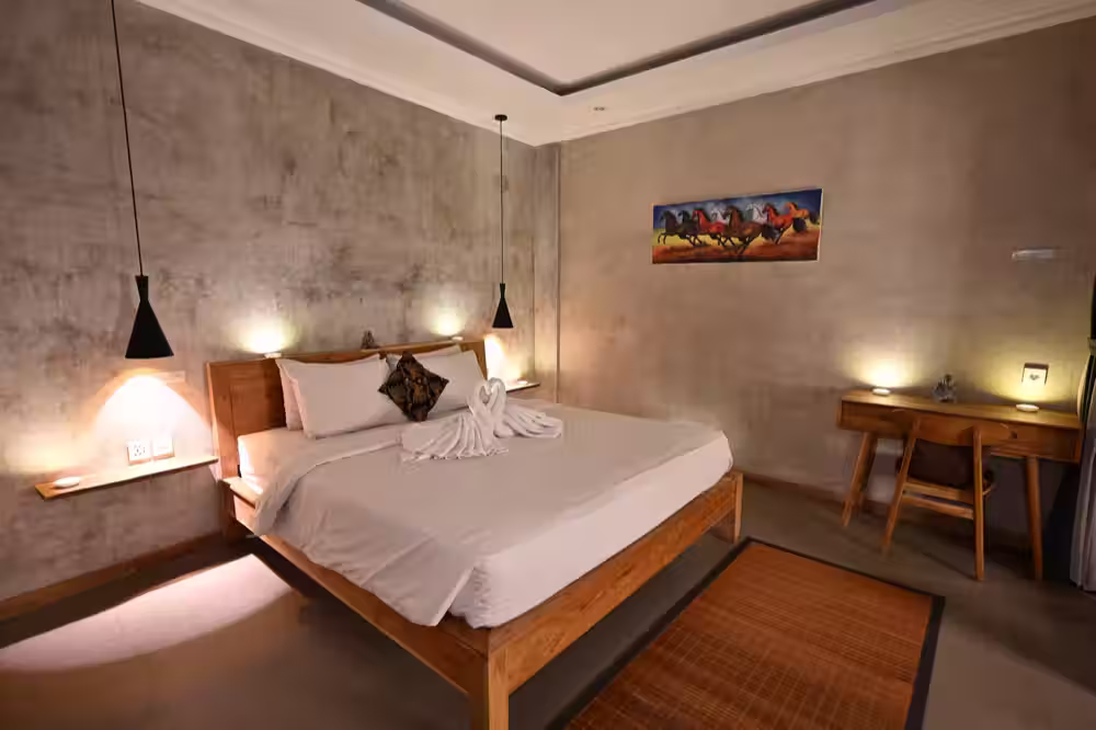 A bedroom with a timber double bed, soft wall lights and a writing desk